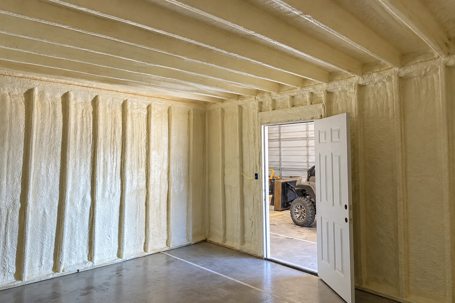 Spray foam coats the walls and ceiling of a commercial space beside an open door.